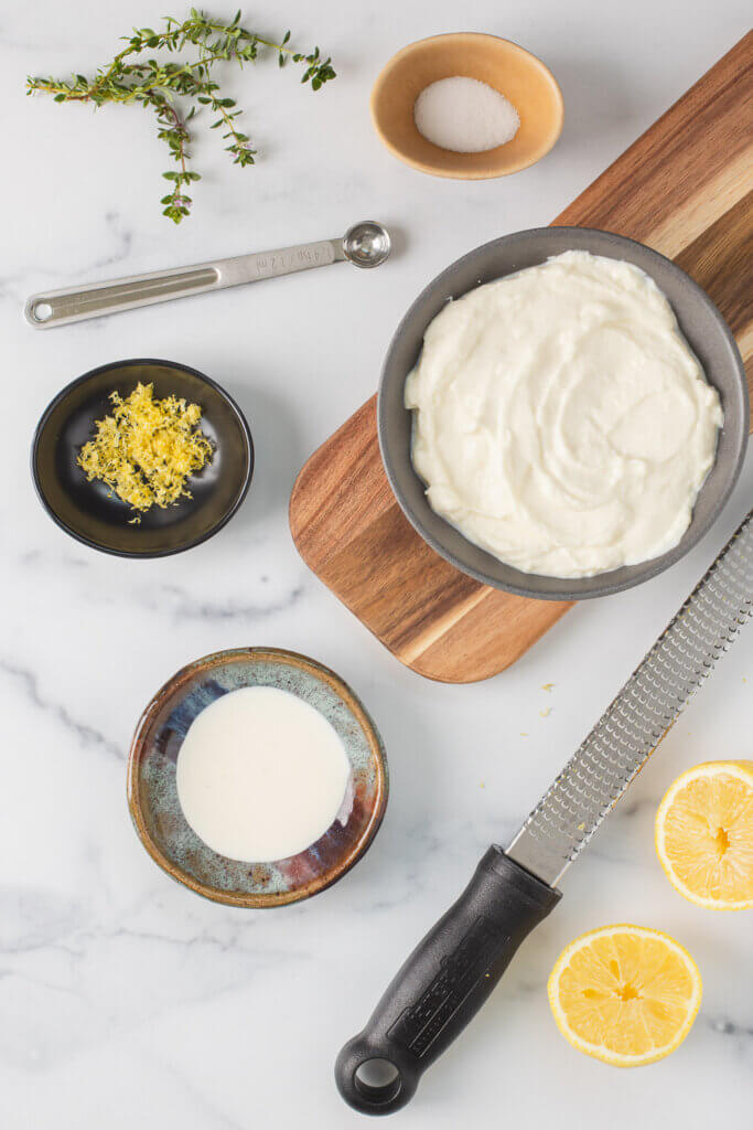 Ingredients for homemade whipped ricotta arranged on a light-colored surface.