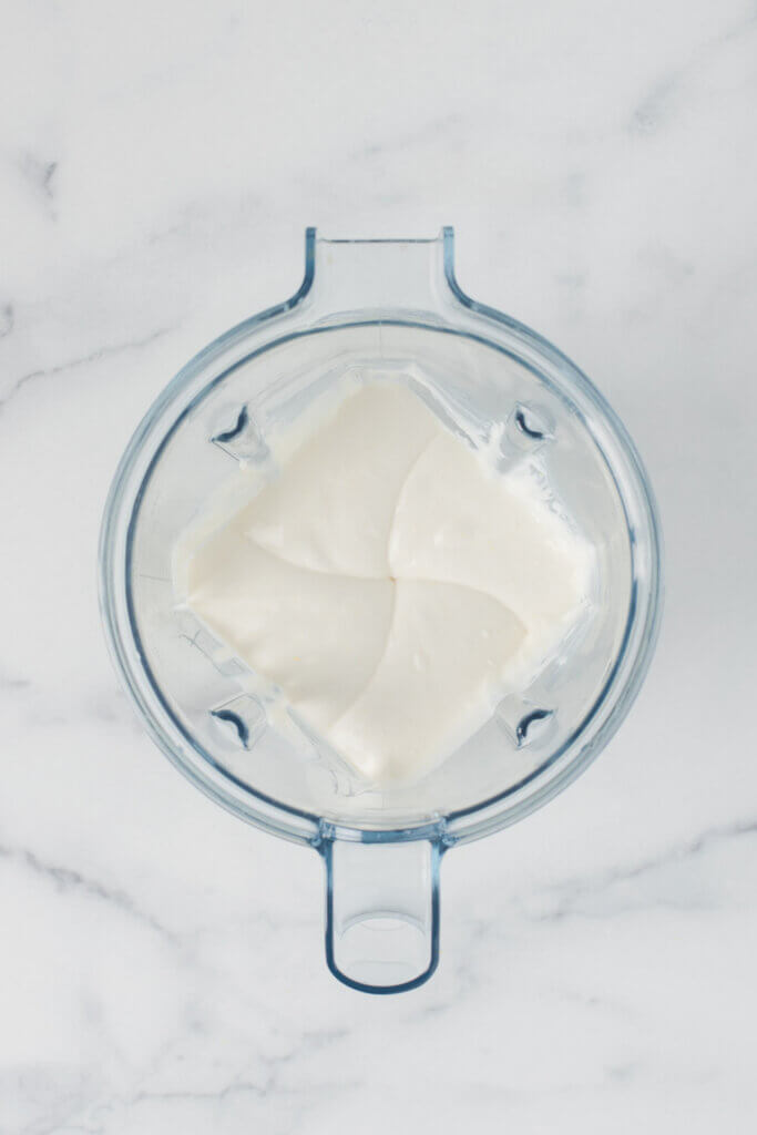 Smooth whipped ricotta in a glass mixing bowl after blending with a blender.