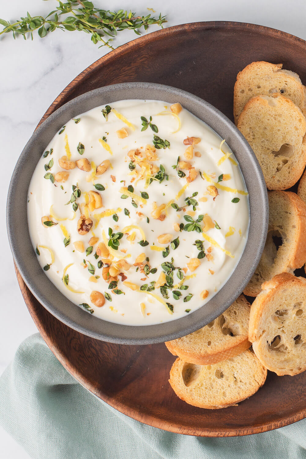 Creamy whipped ricotta garnished with herbs and served alongside slices of toasted bread.