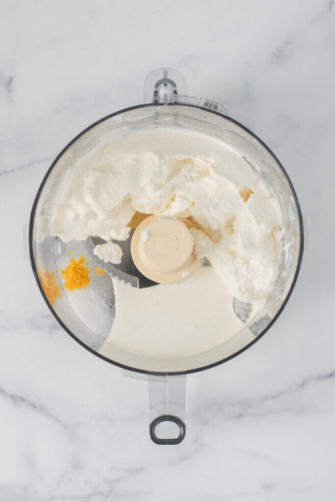 Ricotta cheese and citrus zest in a food processor before blending.