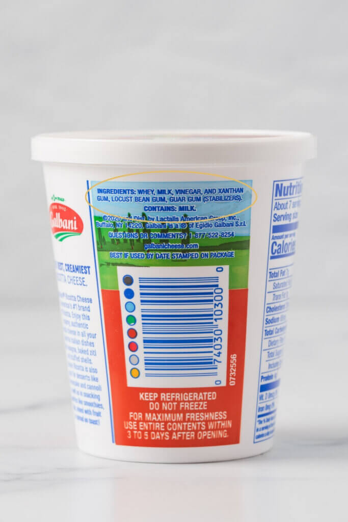 Whole milk ricotta cheese container with the ingredient list circled in yellow, highlighting whey, milk, vinegar, and stabilizers, including xanthan gum, locust bean gum, and guar gum.