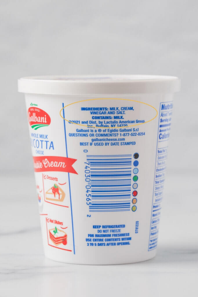 Whole milk ricotta cheese container with the ingredient list circled in yellow, showing only milk, cream, vinegar, and salt, with no added stabilizers.